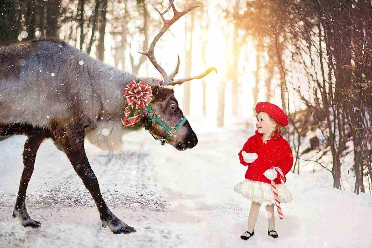 Renna con bambina sulla neve il giorno di Natale